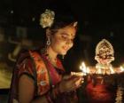 Klečící žena s olejovou lampu do svých rukou oslavy Diwali