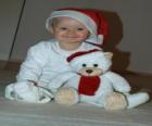 Chlapec s kloboukem Santa Claus se svým plyšovým medvědem