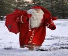 Santa Claus nesoucí velký pytel s dárky Vánoce v lese