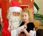 Dívka hovoří do Santa Claus sedí na klíně