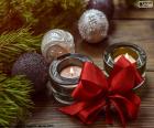 Dvě svíčky spolu s červenou stužkou a jiné vánoční dekorace